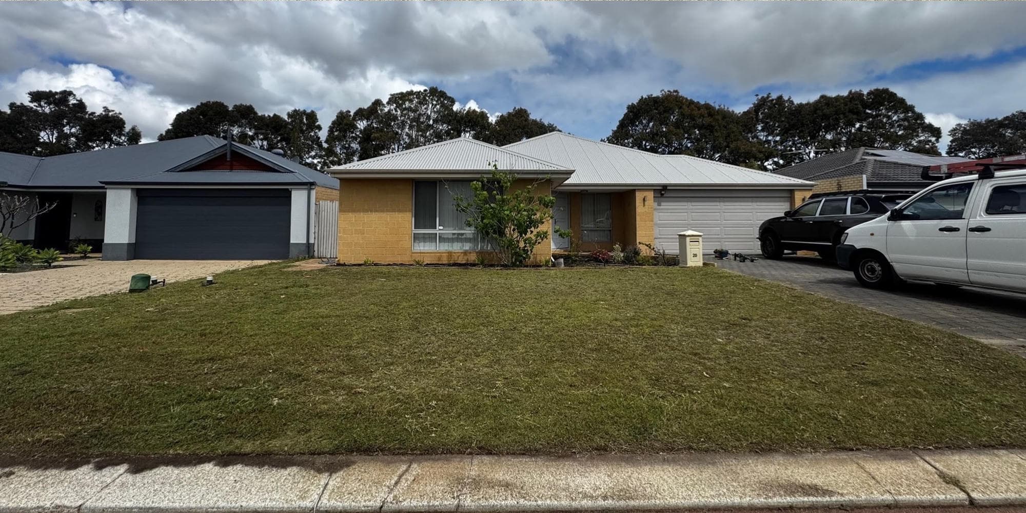 Single-story yellow brick home with a white metal roof and a spacious front lawn.