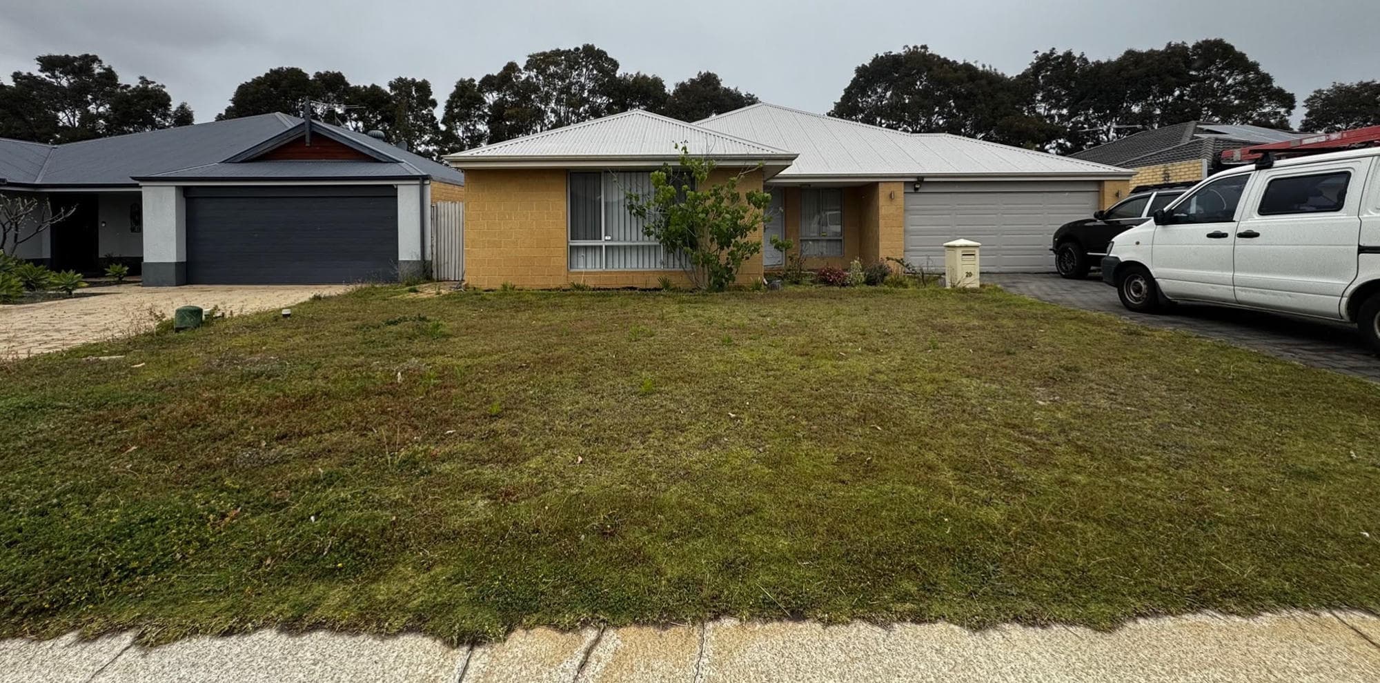 Yellow brick house with a white metal roof and a large green front lawn.